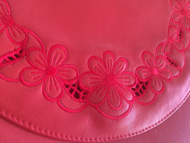 May include: Red leather purse with a decorative embroidered border of red flowers.