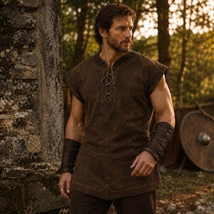 May include: A dark brown sleeveless tunic featuring a lace-up front closure with thin cord ties and a structured hemline, paired with matching dark brown leather-style forearm bracers that wrap around the lower arms with visible stitching details.