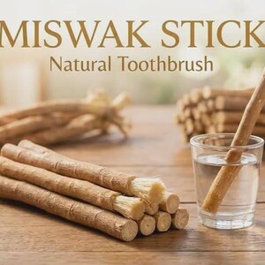 Peut inclure: Une collection de bâtons de Miswak brun clair, avec une extrémité effilochée en poils. Un bâton est placé dans un verre d'eau transparent. Le texte MISWAK STICK Natural Toothbrush est affiché en haut de l'image.