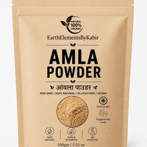 Könnte beinhalten: Ein beigefarbener, wiederverschließbarer Beutel mit Amla-Pulver von EarthElementsByKabir. Das Etikett enthält den Text '100% NATURAL', 'NON GMO', 'GLUTEN FREE', 'VEGAN' und '100gm | 3.52 oz'. Ein rundes Sichtfenster zeigt das hellbraune Pulver.