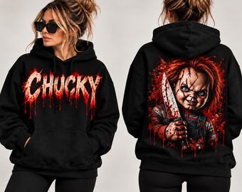 Könnte beinhalten: Ein schwarzer Kapuzenpullover mit dem Wort CHUCKY in einer roten, tropfenden Schrift auf der Vorderseite. Die Rückseite zeigt eine Grafik einer vernarbten Puppe mit roten Haaren, die ein blutiges Messer hält, umgeben von roten Farbspritzern.