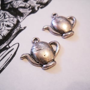 May include: Two silver teapot charms with a detailed design. The charms are perfect for adding a touch of whimsy to jewelry or crafts.