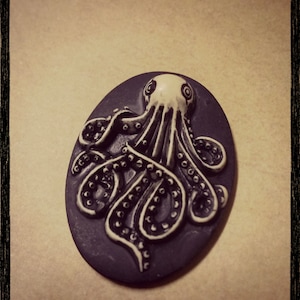 May include: A black and white ceramic octopus figurine with detailed tentacles. The octopus is set against a black background.