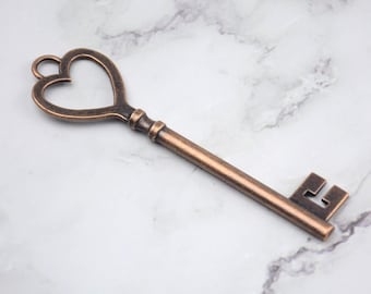 May include: A vintage-style key with a heart-shaped top and a bronze finish. The key has a long, straight shaft and a detailed bit. The heart-shaped design adds a romantic touch to this decorative item.