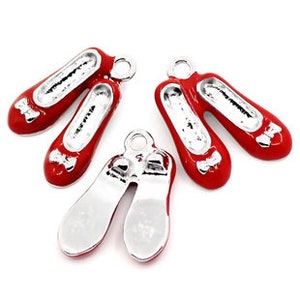 May include: Four red and silver shoe charms with a bow detail. The charms are in the shape of a pair of ballet shoes.