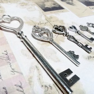 May include: A set of six silver-toned skeleton keys with heart-shaped designs. The keys are arranged on a white background with handwritten text.