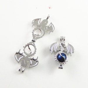 May include: Two silver dragon charm pendants, one with a blue pearl inside. The dragon charms are detailed and have open wings.