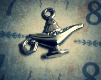 May include: A silver-toned genie lamp charm with intricate details. The lamp has a curved spout and a round handle.