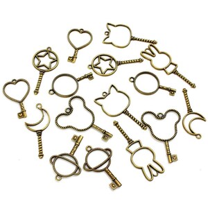 May include: A set of 15 antique gold key charms with various shapes, including hearts, stars, moons, and animal silhouettes. These charms are perfect for jewelry making, scrapbooking, and other craft projects.