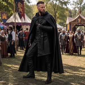 May include: A black leather long coat with a matching hooded cape, worn with black leather gloves and tall black boots. The outfit features a structured bodice with a belt at the waist, a high collar, and a full-length cape secured at the neck.