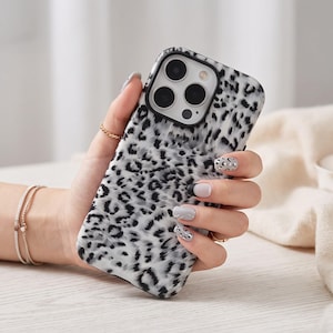Op de afbeelding: Een smartphonehoesje met een zwart-wit luipaardprintpatroon. Het hoesje heeft een rechthoekige vorm met afgeronde hoeken en een uitsparing in de linkerbovenhoek voor de cameralenzen die in de behuizing zichtbaar zijn.