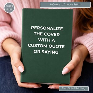May include: A dark green rectangular notebook with a smooth matte finish. The front cover features white text that reads: PERSONALIZE THE COVER WITH A CUSTOM QUOTE OR SAYING. The notebook is held upright, showcasing its solid color and clean design.