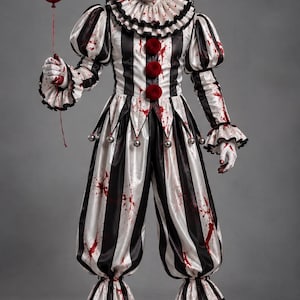 Può includere: Un costume da clown composto da una tuta a righe bianche e nere con colletto a balze, tre pon pon rossi sul petto e campanellini argentati in vita. Il tessuto è schizzato di vernice rossa e include un palloncino rosso e guanti bianchi.