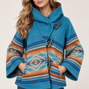 May include: A teal hooded jacket featuring a geometric pattern in shades of orange, blue, and cream. The jacket has wide sleeves, a brown interior lining, and three wooden toggle closures down the front. It is worn with blue denim jeans.