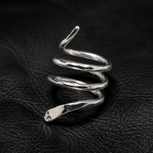 May include: A silver-coloured ring shaped like a coiled snake with a hammered, textured finish. The metal band spirals upwards in three distinct loops, ending in a tapered point at the top and a rounded head at the bottom base of the design.