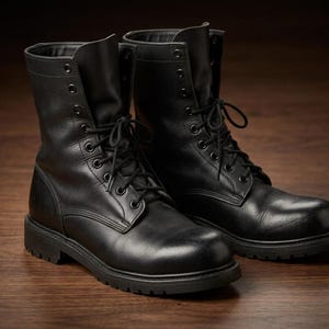 Könnte beinhalten: Ein Paar schwarze Schnürstiefel aus Leder mit hohem Schaft, abgerundeten Zehenkappen und dicken, robusten Gummiprofilsohlen. Die Stiefel verfügen über schwarze Metallösen und passende schwarze Schnürsenkel für einen sicheren Halt.