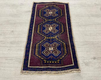 Op de afbeelding: Een rechthoekig vloerkleed met een dieppaarse achtergrond en drie centrale blauwe achthoekige medaillons. Elk medaillon bevat een geometrisch bruin en crèmekleurig patroon. Het kleed is omlijst door een donkerblauwe rand met kleine rode accenten.