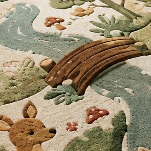 May include: A textured fabric quilt featuring a raised, three-dimensional forest scene. The design includes a winding blue river, a brown wooden bridge, a brown deer, a small hedgehog, and red-capped mushrooms on a cream-coloured background.