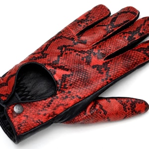 Könnte beinhalten: Ein einzelner Handschuh mit einem leuchtend roten und schwarzen Schlangenhautmuster auf dem Handrücken. Der Handschuh verfügt über eine schwarze Lederinnenfläche, einen kreisförmigen Ausschnitt am Handgelenk und einen kleinen Metalldruckknopf.