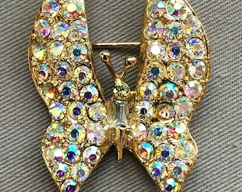 Puede incluir: Un broche de mariposa de oro con diamantes de imitación iridiscentes.