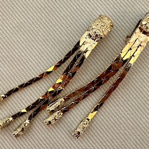 May include: A pair of gold-tone dangle earrings with a chain link design. The earrings have a textured, almost nugget-like, top.