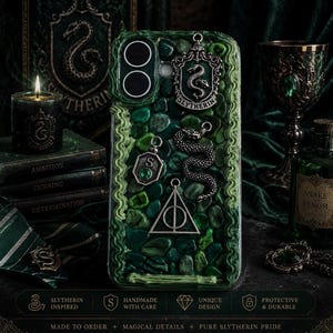 May include: A green phone case featuring a textured surface of small stones, adorned with silver-toned metal charms including a snake crest, a coiled snake, a letter S emblem with a green gem, and a triangular symbol with a circle and line.