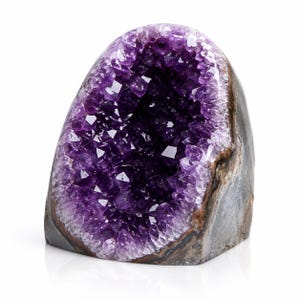 May include: A large, upright amethyst geode featuring a deep purple, crystalline interior cavity. The outer shell of the mineral specimen is composed of rough, dark grey and brown rock, contrasting with the faceted, translucent purple crystals.