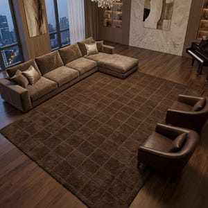 May include: A large, rectangular, dark brown area rug featuring a grid pattern of recessed squares. The rug is positioned on a dark wood floor in a living room setting, surrounded by a brown sectional sofa, two leather armchairs, and a grand piano.