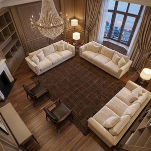 May include: A living room featuring three cream-colored sofas, two dark brown leather armchairs, and a large square brown rug. A crystal chandelier hangs from the ceiling above the seating area, which is surrounded by wood-paneled walls.