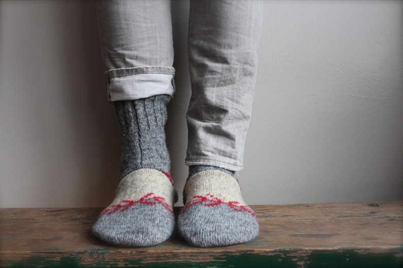 May include: A pair of gray wool socks with red and white accents. The socks are folded down at the top, revealing the gray wool fabric.