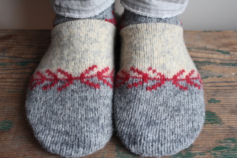 May include: A pair of gray wool slippers with a white and red knit pattern.