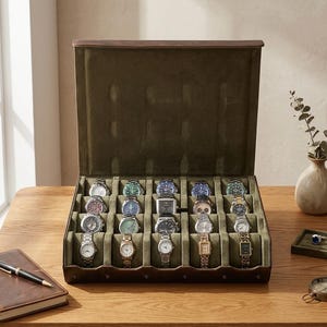May include: A dark brown leather watch display case with an open lid, featuring a soft olive green velvet interior with twenty individual compartments, each containing a wristwatch with various metal bands and different colored watch faces.