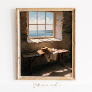 May include: A framed wall art print depicting a rustic stone interior with a wooden bench positioned beneath a window. A straw hat and a white cloth rest on the bench. The window reveals a view of the blue ocean under a bright, cloudy sky.