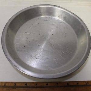 May include: A silver pie plate with a perforated bottom. The plate is 9 inches in diameter.