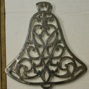 May include: A gold metal bell ornament with a decorative, intricate design. The bell is hollow and has a scalloped edge.