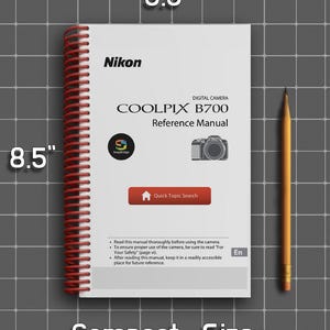 May include: A white Nikon Coolpix B700 reference manual with a red spiral binding. The cover features black text, a camera icon, and a red Quick Topic Search button. It measures 5.5 inches by 8.5 inches, shown next to a yellow pencil.