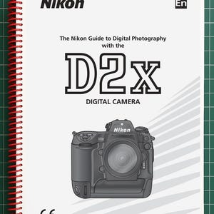May include: A white spiral-bound manual titled The Nikon Guide to Digital Photography with the D2x Digital Camera. The cover features a black and white illustration of a Nikon D2x camera, the Nikon logo, and a CE mark in the bottom left corner.