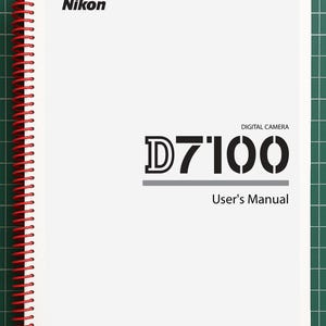 May include: A white Nikon D7100 digital camera user's manual with a red spiral binding. The cover features the Nikon logo in black, the text D7100, the words Digital Camera, User's Manual, and a small square box containing the letters En.