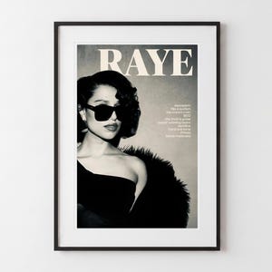 Könnte beinhalten: Ein gerahmtes Schwarz-Weiß-Poster mit dem Wort RAYE in großen Großbuchstaben am oberen Rand. Das Bild zeigt eine Person mit dunkler Sonnenbrille und einem dunklen Oberteil mit strukturiertem Schulterdetail, ergänzt durch eine Liste von Titeln.