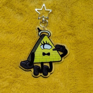 May include: A yellow triangular character keyring featuring a single large eye, a black bow tie, and black limbs. The character is depicted with a top hat and a halo, attached to a silver-coloured star-shaped metal clasp for securing to items.