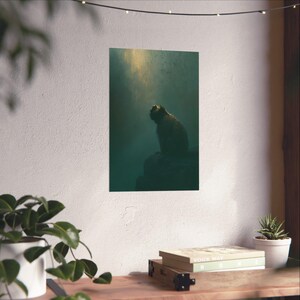 Könnte beinhalten: Ein vertikaler Wandkunstdruck mit einer dunklen, stimmungsvollen Szene eines Affen, der auf einem Felsvorsprung sitzt und zu einer hellen, goldenen Lichtquelle aufblickt, die durch die tiefblaue und schattige Atmosphäre des Raumes dringt.
