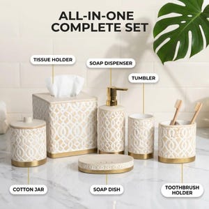 May include: A bathroom accessory set labeled ALL-IN-ONE COMPLETE SET, including a tissue holder, soap dispenser, tumbler, cotton jar, soap dish, and toothbrush holder. Each piece features a cream-colored geometric pattern and gold-tone base.