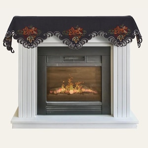 May include: A black fabric mantel scarf featuring an embroidered autumn leaf pattern in shades of orange, red, and green. The scarf has a scalloped edge with intricate cutwork detailing and is draped over a white fireplace mantel.