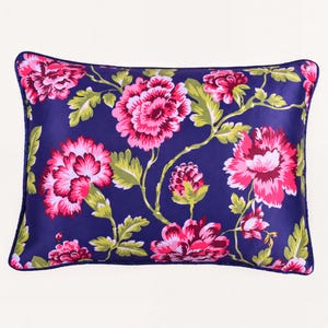 May include: A rectangular throw pillow featuring a deep navy blue background with a vibrant floral pattern. The design includes large, layered pink and magenta peony-like flowers with light green leaves and stems, finished with a navy blue piped edge.