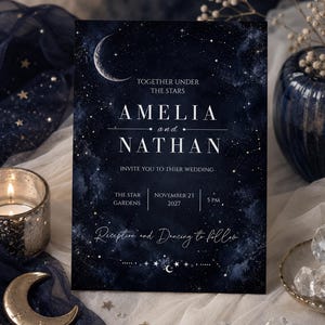 May include: A rectangular wedding invitation card featuring a dark navy blue night sky background with a crescent moon and star constellations. The text reads: TOGETHER UNDER THE STARS AMELIA and NATHAN INVITE YOU TO THIER WEDDING THE STAR GARDENS NOVEMBER 23 2027 5 PM Reception and Dancing to follow.