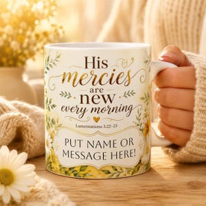 May include: A white ceramic mug featuring a floral design with yellow and green leaves and flowers. The text reads: His mercies are new every morning, Lamentations 3:22-23, and a placeholder box with the text: PUT NAME OR MESSAGE HERE!