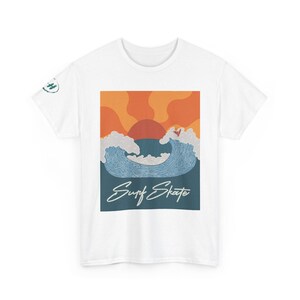 May include: A white short-sleeve t-shirt featuring a central graphic of a sunset over blue ocean waves with a small surfer silhouette. The text Surf Skate is printed in white script below the waves. A small circular logo is on the right sleeve.