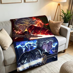 May include: A rectangular throw blanket featuring a split-screen graphic design. The top half displays a character with light hair in red armor holding a glowing sword. The bottom half shows a character with silver hair in dark armor with blue lightning.