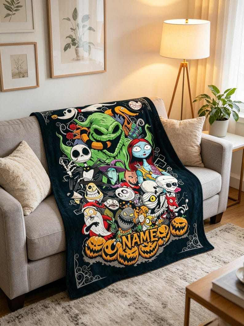 May include: A black fleece throw blanket featuring a colorful graphic print of characters from The Nightmare Before Christmas, including Jack Skellington, Sally, and Oogie Boogie, with a cluster of orange jack-o'-lanterns and the word NAME.