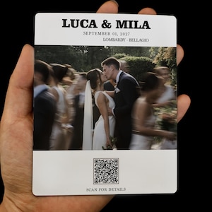 May include: A rectangular wedding invitation card featuring the names LUCA & MILA, the date SEPTEMBER 01, 2027, and the location LOMBARDY · BELLAGIO. The center displays a photograph of a couple kissing, and the bottom includes a QR code with the text SCAN FOR DETAILS.